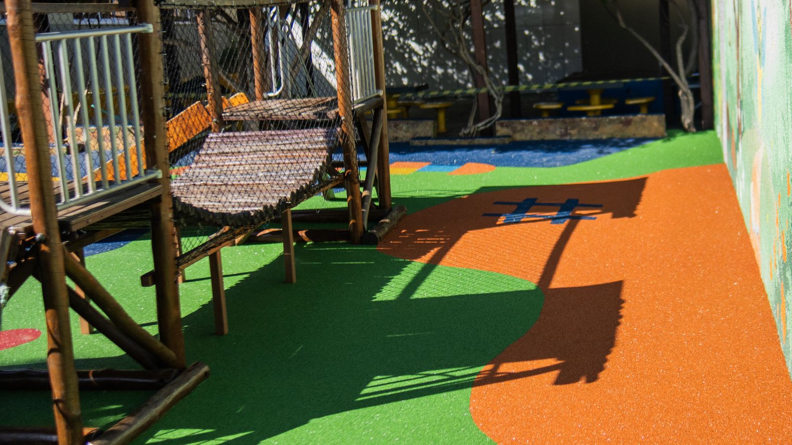 Parquinho com brinquedo de madeira sobre piso monolítico colorido