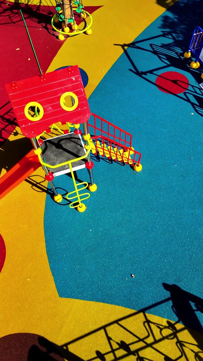 Brinquedos sobre piso de borracha colorido em praça inclusiva de Vitória